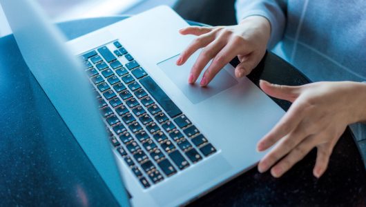 Woman's hands typing text on a laptop